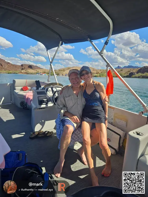 A shared RealReel photo of a couple on a pontoon boat on a lake, with @mark's watermark and a QR code back to the post
